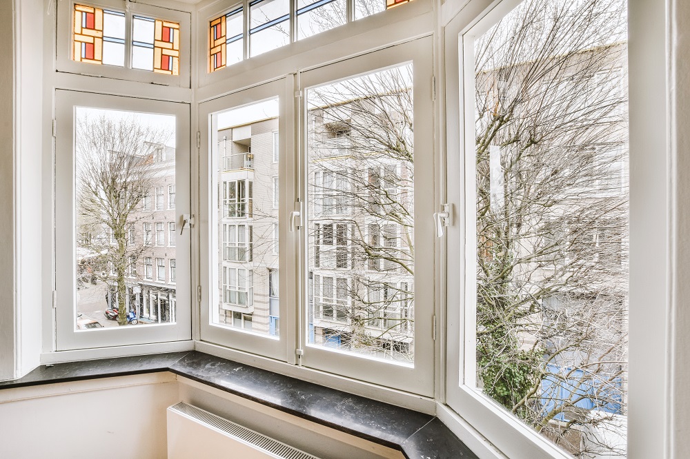 Empty room with window and radiator - BVG Bright bay window with white frames overlooking a city street and bare trees outside.