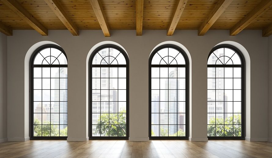 Room with four arched windows, exposed wooden beams, and a city skyline outside.