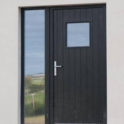 Front door with vertical panels, a slim glass side panel on the left, and a small square window in the door